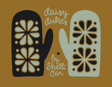 Load image into Gallery viewer, A graphic design featuring two oven mitts with floral cutout patterns on a solid brown background, with the text 'daisy dukes by Shelli Can' written in a white script font.