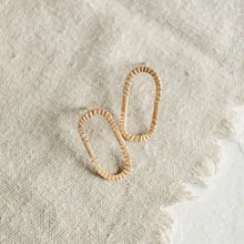 Load image into Gallery viewer, Pair of gold hoop earrings on a textured beige surface
