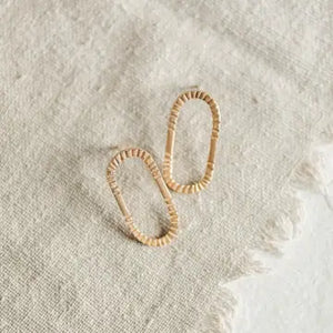 Pair of gold hoop earrings on a textured beige surface