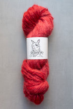 Load image into Gallery viewer, Red skein of yarn with a label on a gray background