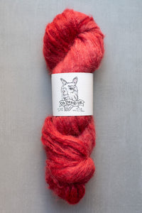 Red skein of yarn with a label on a gray background