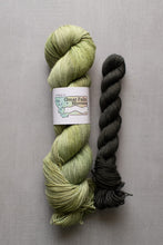 Load image into Gallery viewer, Two skeins of yarn, one green and one black, on a gray background with a label reading 'Great Falls, Montana'.