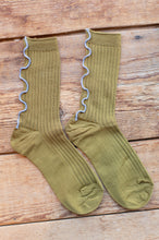Load image into Gallery viewer, Pair of green socks with ruffled edges on a wooden surface