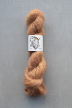 Load image into Gallery viewer, Skein of brown yarn with a label on a gray background