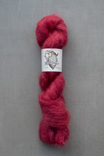 Load image into Gallery viewer, Red skein of yarn with a label on a gray background