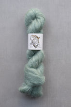 Load image into Gallery viewer, Light green skein of yarn with a label on a gray background
