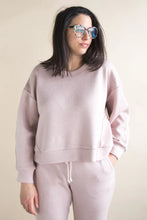 Load image into Gallery viewer, Woman wearing a light pink sweatshirt and pants against a beige background