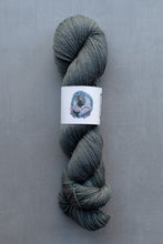 Load image into Gallery viewer, Gray skein of yarn with a label on a gray background