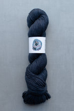 Load image into Gallery viewer, Dark blue skein of yarn with a label on a gray background