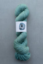 Load image into Gallery viewer, Teal skein of yarn with a label on a gray background
