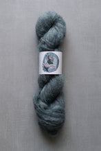Load image into Gallery viewer, Blue skein of yarn with a label on a gray background