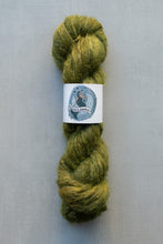 Load image into Gallery viewer, A skein of fuzzy olive green yarn with a white paper label in the center, photographed against a plain light gray background.