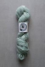 Load image into Gallery viewer, Light green skein of yarn with a label on a gray background