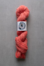 Load image into Gallery viewer, Peach-colored yarn skein with a label on a gray background