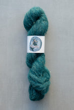 Load image into Gallery viewer, A skein of teal blue-green yarn with a white paper label in the center, photographed against a neutral gray background.