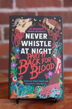 Load image into Gallery viewer, A hardcover book titled "Never Whistle at Night: Part II Back for Blood" displayed on a small black stand against a brick wall background. The cover features a dark background with vibrant, whimsical illustrations of a wolf, a bird, a deer, a fish, and other fantasy creatures in red, pink, blue, green, and yellow tones.