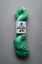 Load image into Gallery viewer, Green skein of yarn with a label on a gray background