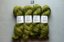 Load image into Gallery viewer, Four skeins of olive green yarn with white paper bands showing a dog illustration, arranged in two rows on a light gray background with the number 13 above them.