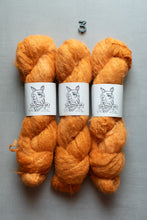 Load image into Gallery viewer, Three skeins of fluffy orange yarn with white paper bands showing the 'Old Shaman' logo, arranged vertically on a gray background with a small metal '3' at the top.
