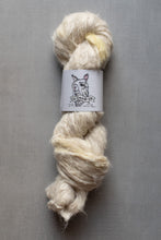 Load image into Gallery viewer, A skein of fluffy, natural-colored yarn wrapped with a white paper label featuring a llama illustration