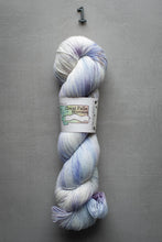 Load image into Gallery viewer, Blue and purple skein of yarn with a label on a gray background