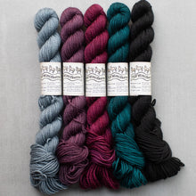 Load image into Gallery viewer, Five skeins of yarn in different colors arranged vertically on a light gray fabric background. The colors are light blue, mauve, teal, black, teal, and mauve, each with a white paper label in the center.