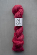 Load image into Gallery viewer, Red skein of yarn with a label on a gray background