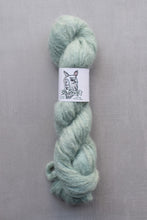 Load image into Gallery viewer, Light green skein of yarn with a label on a gray background