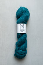 Load image into Gallery viewer, Teal skein of yarn with a label on a gray background