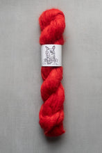 Load image into Gallery viewer, Red skein of yarn with a label on a gray background