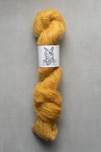 Load image into Gallery viewer, Mustard yellow skein of yarn with a label on a gray background