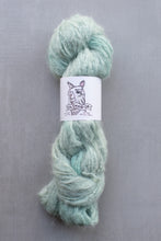 Load image into Gallery viewer, Light green skein of yarn with a label on a gray background