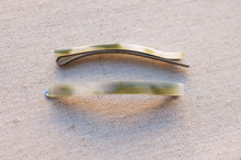 Load image into Gallery viewer, Two metallic hair clips on a textured beige surface