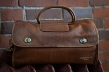Load image into Gallery viewer, Brown leather bag with gold hardware on a brick wall background