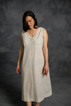 Load image into Gallery viewer, Woman wearing a beige sleeveless dress against a dark background