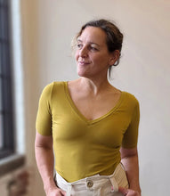 Load image into Gallery viewer, Woman wearing a yellow shirt standing indoors with a neutral background