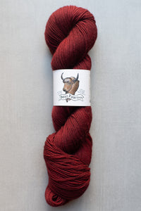 Red skein of yarn with a label featuring a bear design on a light gray background