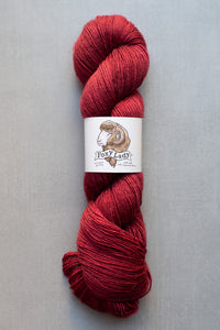 Red skein of yarn with a label on a gray background