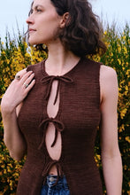 Load image into Gallery viewer, Woman wearing a brown sleeveless top with a tie design against a yellow flower background