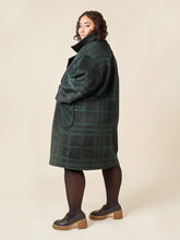 Load image into Gallery viewer, Person wearing a green plaid coat on a beige background