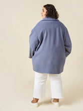 Load image into Gallery viewer, Person wearing a blue coat and white pants on a beige background