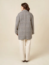 Load image into Gallery viewer, Person wearing a checkered coat and white pants on a beige background