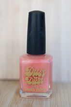 Load image into Gallery viewer, Pink nail polish bottle with black cap on a wooden surface