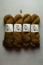 Load image into Gallery viewer, Four skeins of chunky yarn in a warm mustard-brown color, arranged side by side on a light gray background. Each skein is wrapped with a white paper label featuring a dog illustration and the brand name 'Fishbone'.