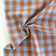 Checkered fabric with small heart patterns on a light background, featuring the brand 'Tableism'.