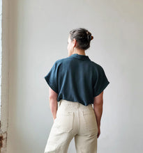 Load image into Gallery viewer, Person wearing a dark blue shirt and beige pants against a plain wall.