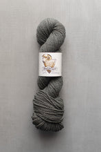 Load image into Gallery viewer, Gray skein of yarn with a label on a gray background