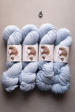 Load image into Gallery viewer, Four skeins of light blue yarn with labels on a neutral background