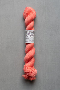 Peach-colored skein of yarn with a label on a gray background