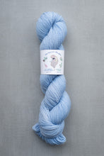 Load image into Gallery viewer, Light blue skein of yarn with a label on a gray background